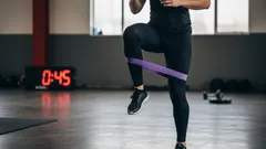 Person tränar med gummiband inomhus, styrketräning och konditionsträning